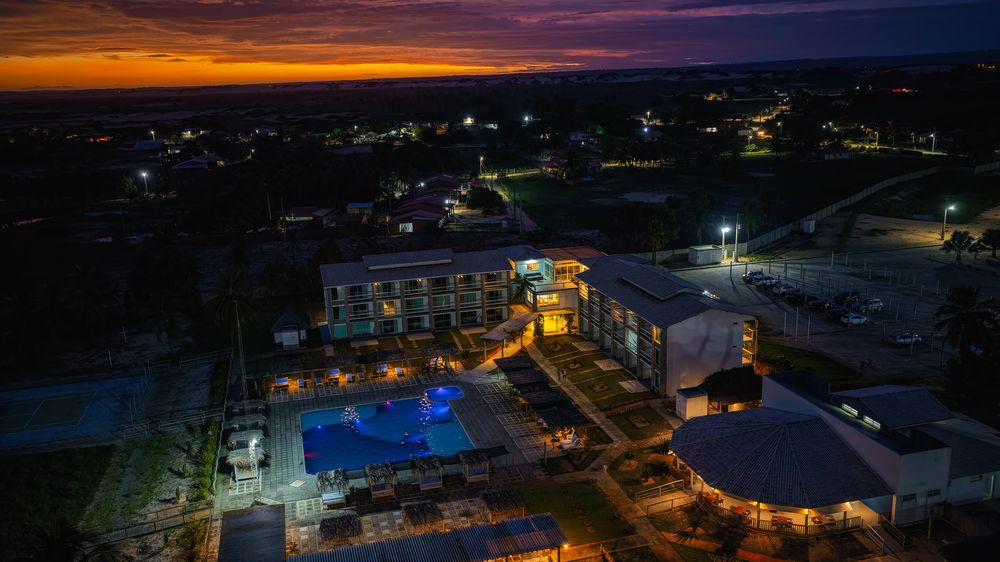 Vista aérea do hotel ao pôr do sol, com as luzes acesas